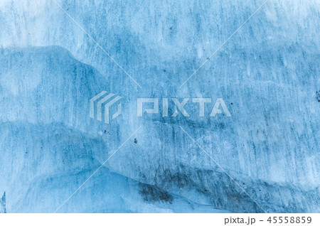 Close-up wall of a centuries-old glacier with a structure of stripes and bubbles. Ice blue light 45558859