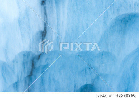 Close-up blurred wall of a centuries-old glacier with a structure of stripes and bubbles. Ice blue Close-up blurred wall of a centuries-old glacier with a structure of stripes and bubbles. Ice blue 45558860