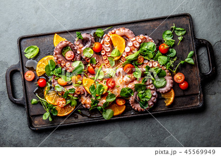 Whole octopus salad with orange, tomatoes and cress salad served on board with wine Whole octopus salad with orange, tomatoes and cress salad served on board with wine 45569949