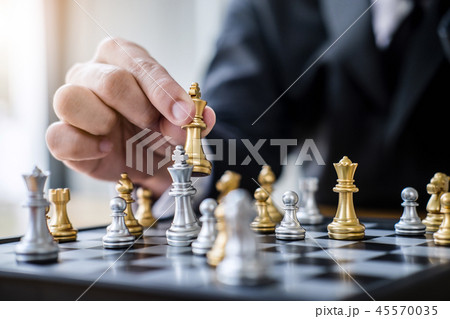 Hands of confident businessman playing chess game to development 45570035