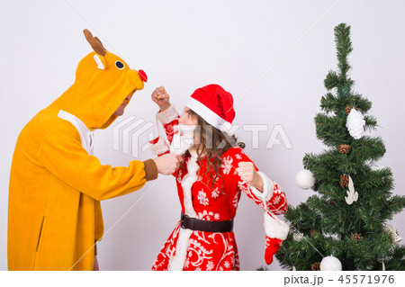 Holiday, Christmas and joke concept - Funny man in deer costume and woman in Santa Claus costume 45571976