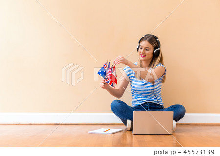 Young woman holding English speaking country flags with laptop Young woman holding English speaking country flags with laptop 45573139