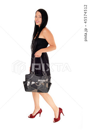 Woman walking in black dress and purse Woman walking in black dress and purse 45574512