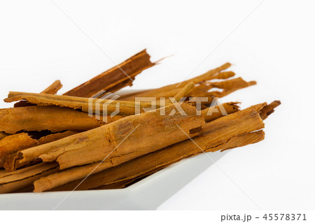 Dry cinnamon sticks in a small white dish isolated 45578371
