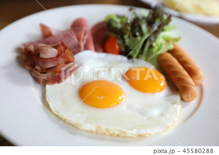 Breakfast set with fried eggs, bacon, sausages, beans, toasts, fresh salad and fruit on wood table 45580288
