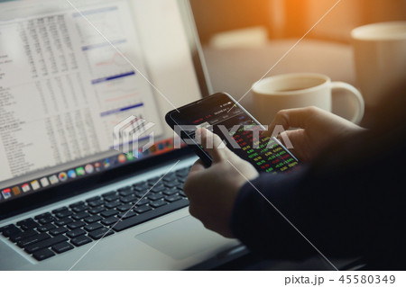 trading online on smartphone and notebook with business woman hand 45580349