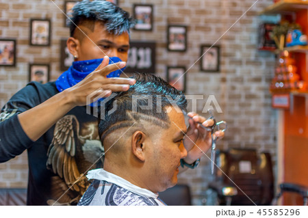Barber haircut a customer at barbershop 45585296