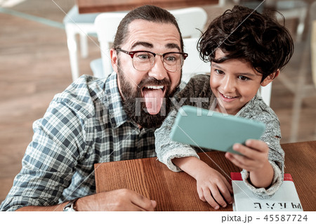 Cute little son holding phone making photo with his father 45587724