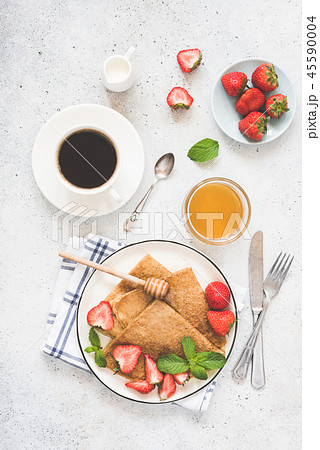 Crepes or blini with honey, strawberries and cup of coffee 45590004