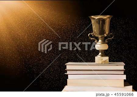 Golden trophy on pile of books, against blackboard 45591066