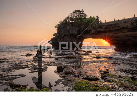 Tourist poses on seashore at sunset Tourist poses on seashore at sunset 45591628
