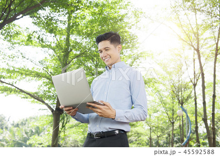 Handsome asian businessman using laptop outdoors Handsome asian businessman using laptop outdoors 45592588