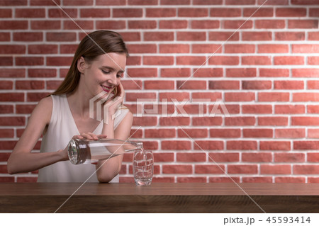 Woman pouring water from bottle into glass  45593414