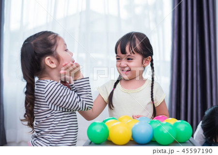 Two little girls playing small toy balls in home together. Educa Two little girls playing small toy balls in home together. Educa 45597190