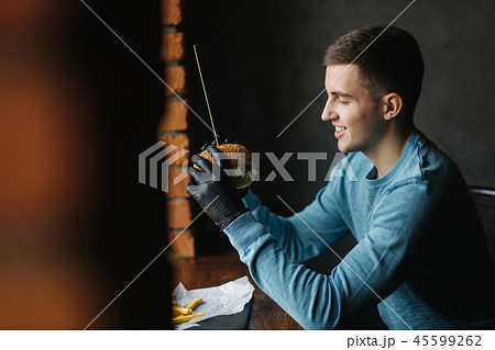 Man in black gloves takes a burger in his hands. Vegetarian burger with vegetables. Fresh healthy 45599262