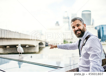 Hipster businessman standing by the river in London, pointing at seagull. 45601807