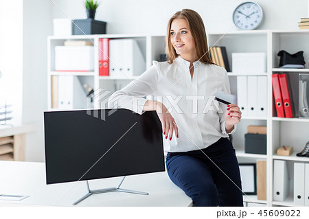 A young girl sat down on the table and holding a Bank card. A young girl sat down on the table and holding a Bank card. 45609022