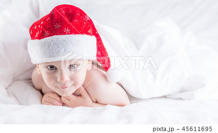 Baby boy with santa hat on bed under white duvet. Baby boy with santa hat on bed under white duvet. 45611695