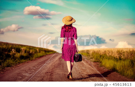 girl with suitcase waking on rural road girl with suitcase waking on rural road 45613613