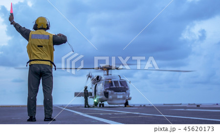 Signal man give a signal to helicopter on the deck 45620173
