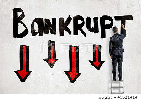 A back view of a man in suit standing on a ladder and writing 'Bankrup' on a wall with four red A back view of a man in suit standing on a ladder and writing 'Bankrup' on a wall with four red 45621414