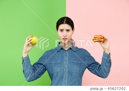 Diet. Dieting concept. Healthy Food. Beautiful Young Woman choosing between fruits and unhelathy Diet. Dieting concept. Healthy Food. Beautiful Young Woman choosing between fruits and unhelathy 45627202