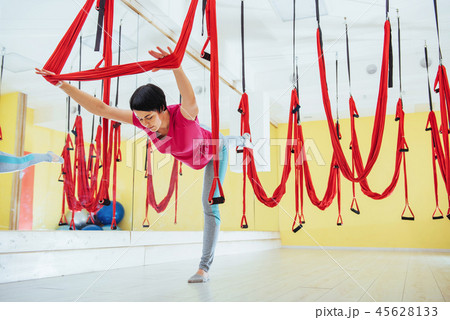 Young beautiful woman practicing yoga Fly with a hammock in the bright studio. The concept of mental Young beautiful woman practicing yoga Fly with a hammock in the bright studio. The concept of mental 45628133