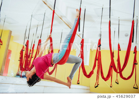 Young beautiful woman practicing yoga Fly with a hammock in the bright studio. The concept of mental Young beautiful woman practicing yoga Fly with a hammock in the bright studio. The concept of mental 45629037