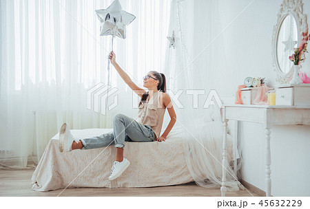 Closeup cute brunette girl in the studio, smiling broadly and playing with transparent and silver 45632229