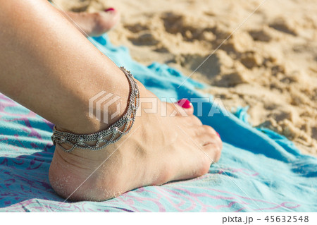 Ankle bracelet on foot with nail polished on beach Ankle bracelet on foot with nail polished on beach 45632548