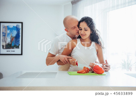 Beautiful young couple grinds vegetables together in the kitchen. 45633899