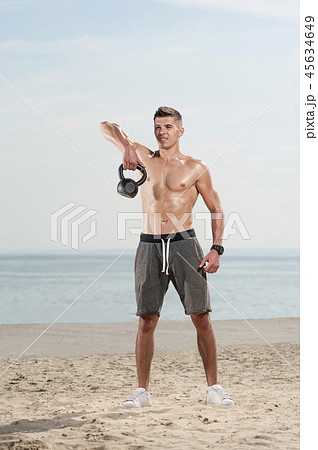 Man with a naked body doing kettlebell exercise 45634649