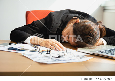 Businesswoman sleeping at work desk with laptop after lunch time. Businesswoman sleeping at work desk with laptop after lunch time. 45635707