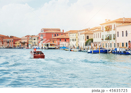 Green water channel with gondolas and colorful facades of old medieval buildings in the sun in Green water channel with gondolas and colorful facades of old medieval buildings in the sun in 45635725