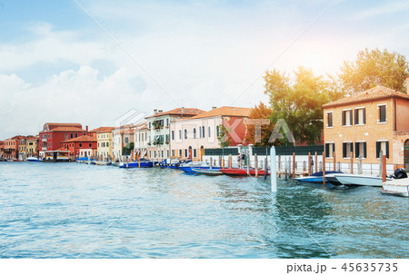 Green water channel with gondolas and colorful facades of old medieval buildings in the sun in Green water channel with gondolas and colorful facades of old medieval buildings in the sun in 45635735