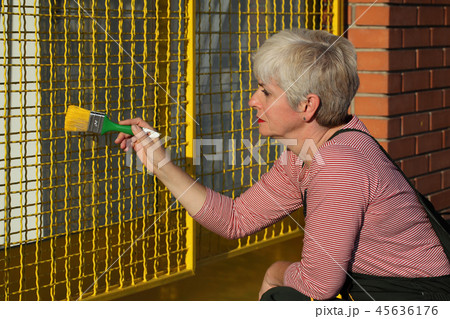 Worker painting metal protective net to yellow color 45636176