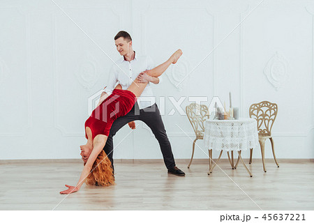 Young beautiful woman in a red dress and a man dancing, isolated on a white background. 45637221