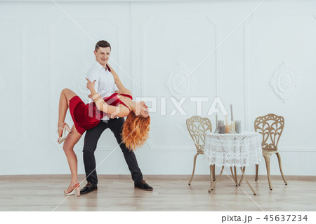 Young beautiful woman in a red dress and a man dancing, isolated on a white background. 45637234