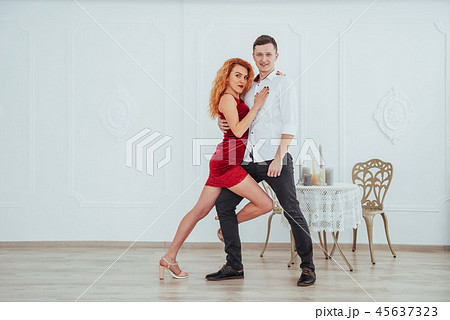 Young beautiful woman in a red dress and a man dancing, isolated on a white background. Young beautiful woman in a red dress and a man dancing, isolated on a white background. 45637323