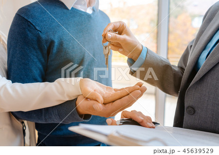 Realtor woman giving house keys to couple, closeup Realtor woman giving house keys to couple, closeup 45639529