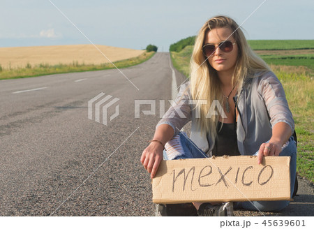 Beautiful girl hitchhiking on the road traveling. Beautiful girl hitchhiking on the road traveling. 45639601