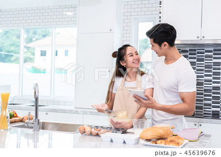 Asian couples cooking and baking cake together in kitchen room a 45639676