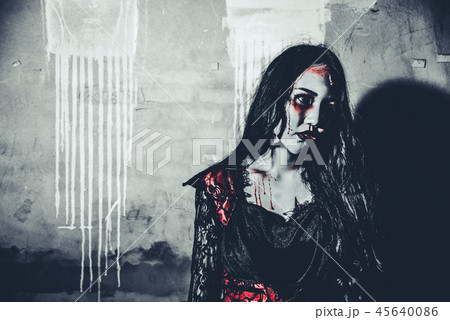 Female zombie corpse standing in front of grunge wall in abandon Female zombie corpse standing in front of grunge wall in abandon 45640086