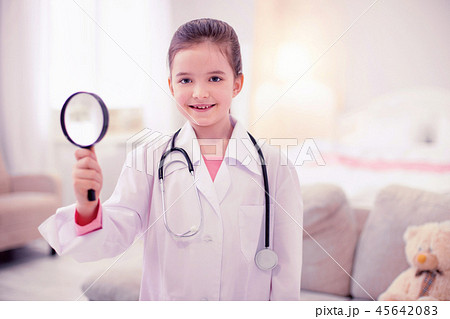 Little girl holding magnifying glass pretending to be a doctor 45642083