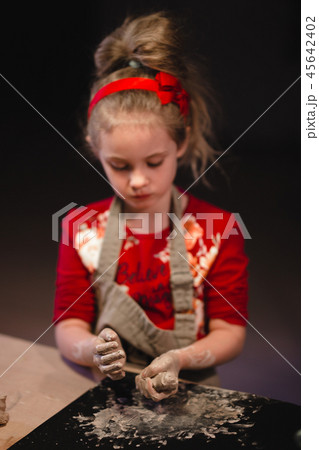 Young seven years old girl in pottery workshop creating a bowl from clay. Pottery workshop for kids 45642402