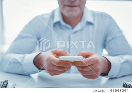 Businessman in blue shirt texting on white phone Businessman in blue shirt texting on white phone 45643044