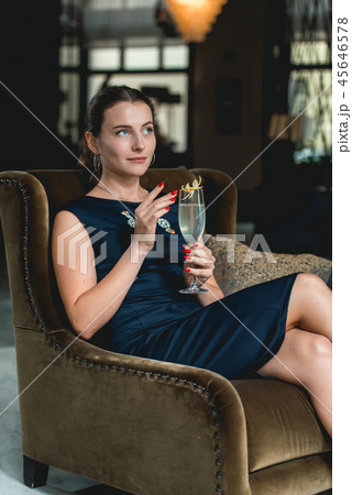 Fashionable gorgeous girl in a dark blue dress drinking cocktail in a luxery hotel lobby bar Fashionable gorgeous girl in a dark blue dress drinking cocktail in a luxery hotel lobby bar 45646578