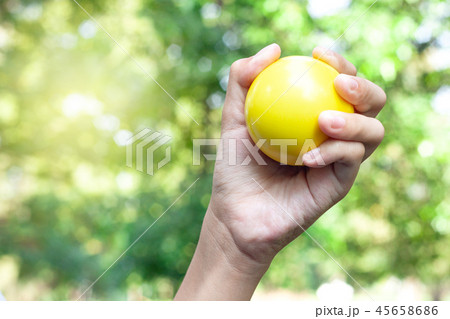 Hand holding a yellow plastic ball 45658686