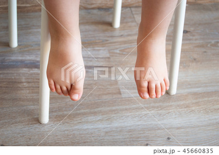 Feet of a child sitting in a chair 45660835