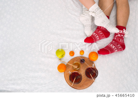 Soft photo of woman and man on the bed with tea and fruits, top view point. Female and male legs in 45665410